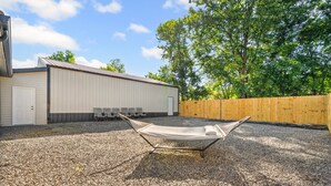 A hammock on gravel, a building with a door, and a wooden fence. - Extended Stay Near Fort Campbell | 2BR (1579 Mary Beth Ln) (Clarksville)