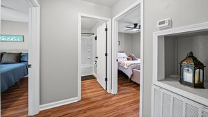 A hallway with a bed on the left, a bathroom with a shower and toilet, and a radiator with a lantern on the right. - Extended Stay Near Fort Campbell | 2BR (1579 Mary Beth Ln) (Clarksville)