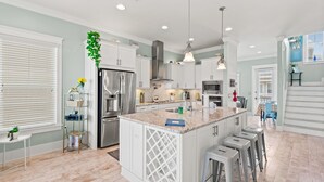 A modern kitchen with white cabinetry, a central island, stainless steel appliances, and bar stools. - 🌊🏖️ Sea Haven | Sound Views, Firepit + Community Pool | Navarre Beach (Navarre Beach)