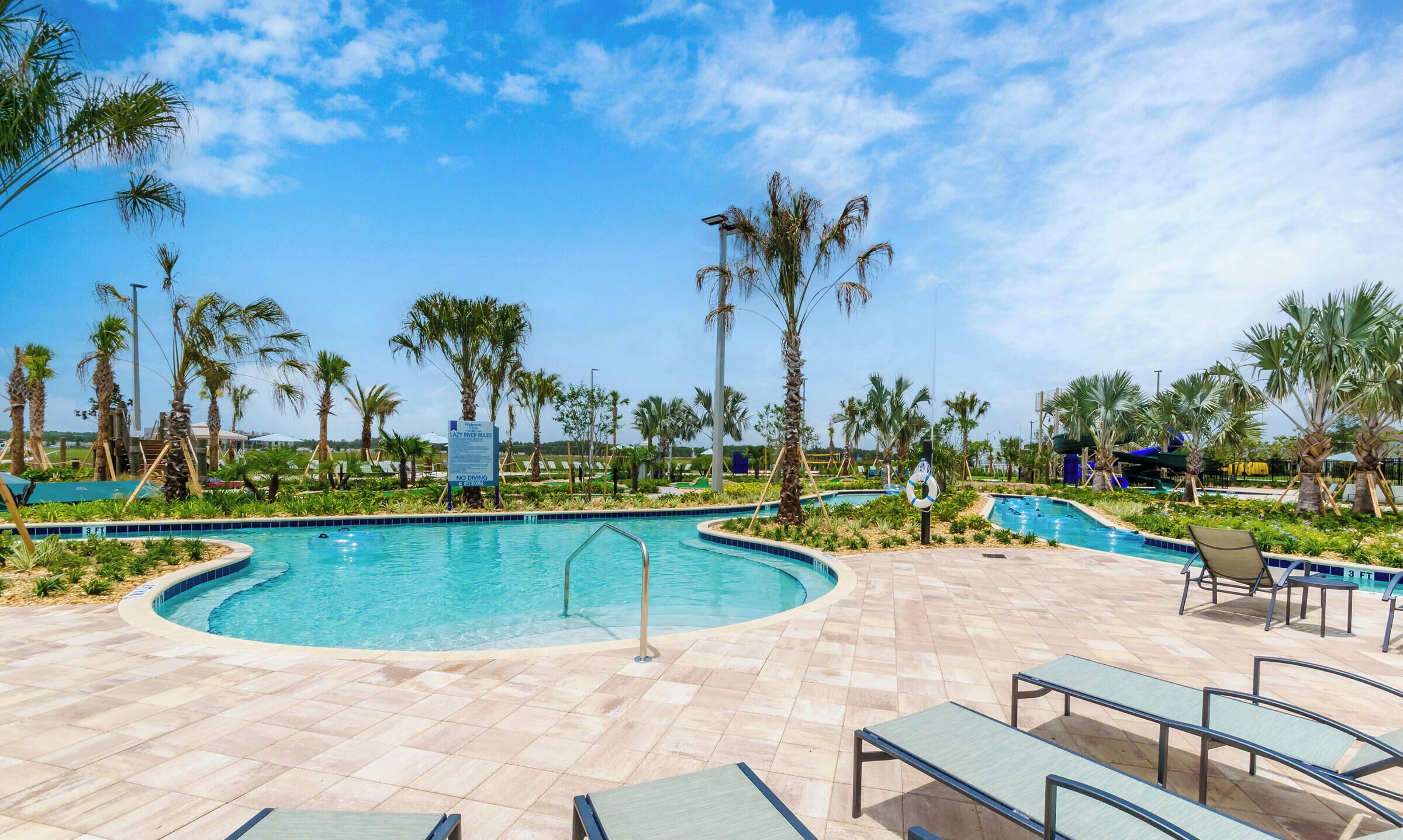 A pool area with palm trees, lounge chairs, and a sign indicating no diving.
