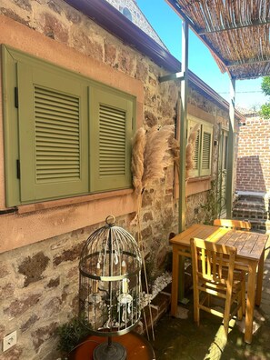 Un espacio al aire libre rústico con pared de piedra, mesa y sillas de madera.