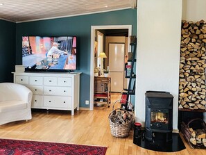 A living room with a television, a white sofa, a fireplace, and a wooden floor. - 4 Star Holiday Home in Nassjo (Nassjo)