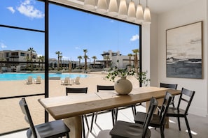 A dining area with a view of a pool and beach, featuring a wooden table and black chairs. - Barefoot Beach Bungalow: Direct Beach Access (St. George)