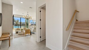 Un interior moderno con una escalera, vistas a una piscina y una sala de estar con muebles.
