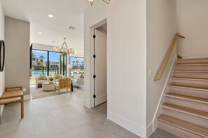 Ein modernes Interieur mit Treppe, Blick auf einen Pool und einer möblierten Wohnbereiches.