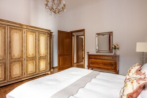Een slaapkamer met een groot bed, een houten garderobe, een dressoir en een spiegel.