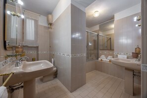 Een moderne badkamer met twee wasbakken, een douchecabine van glas en een grote spiegel.