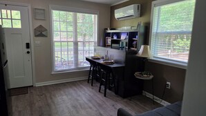 A compact kitchen with a dining area, a bar, and a seating area with a lamp. - Magnolia Meadows (Hampstead)