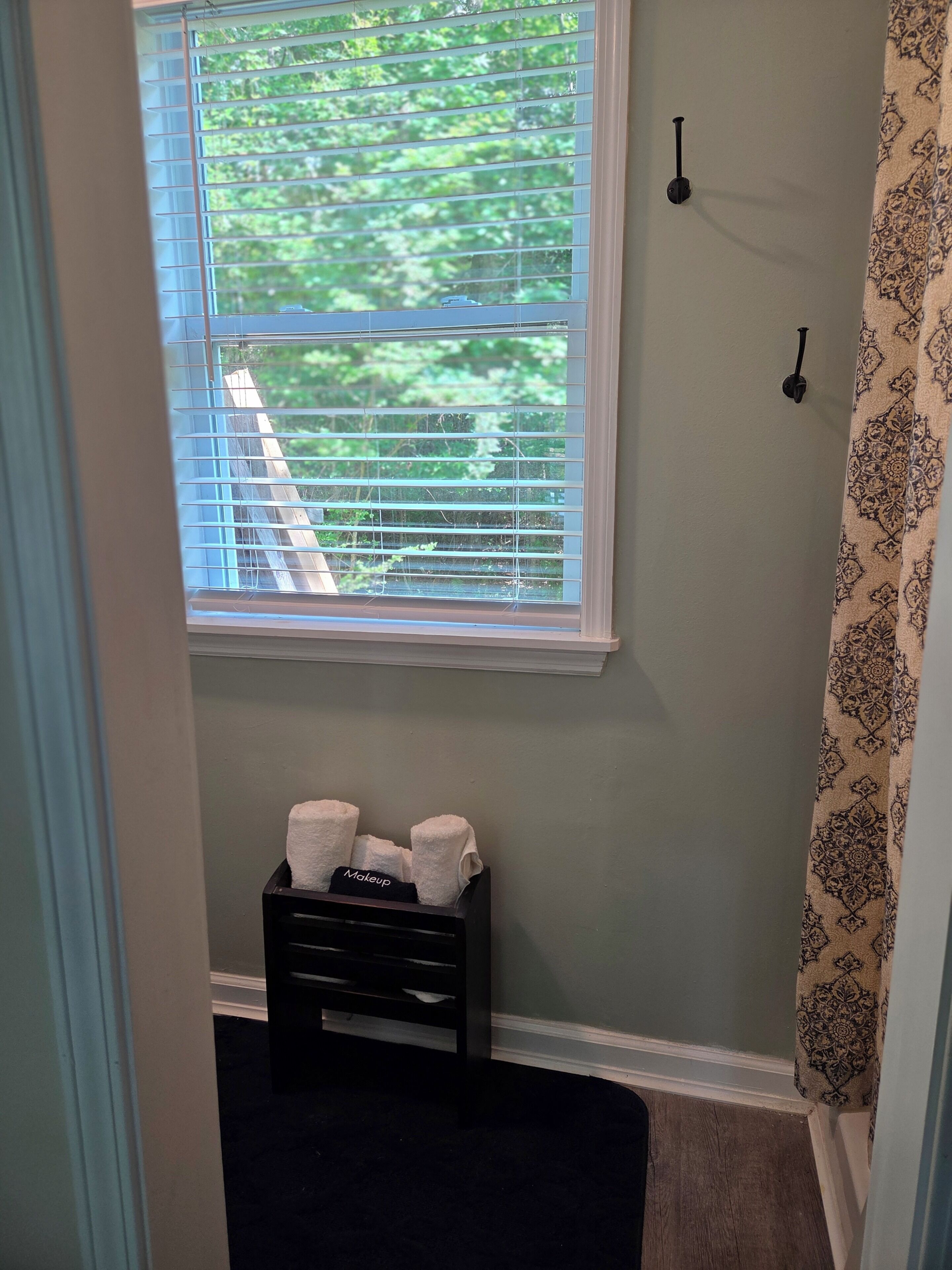 A bathroom with a window, a towel rack, and a black storage unit with towels.