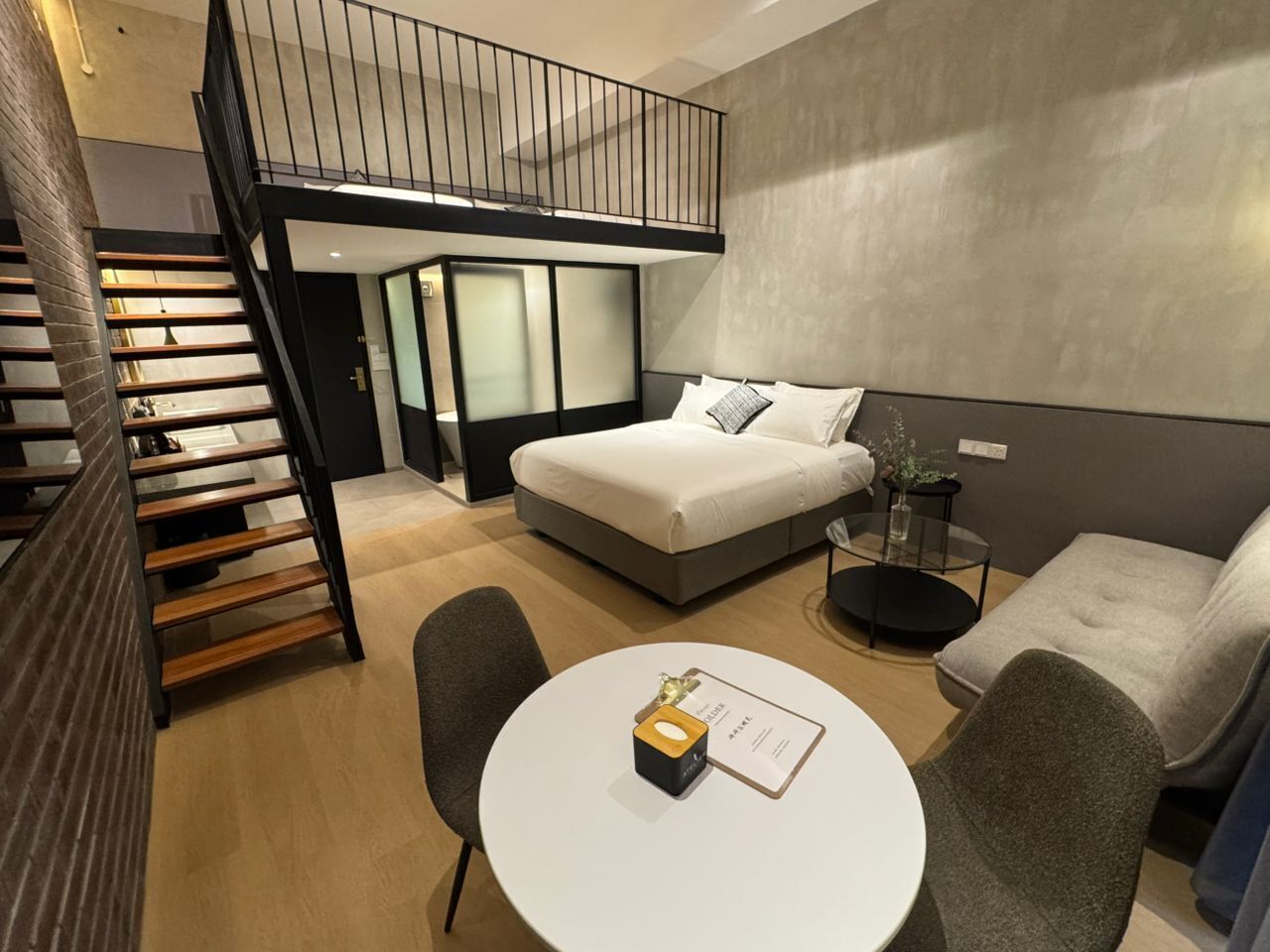 A modern bedroom with a bunk bed, a round dining table, and a small seating area.