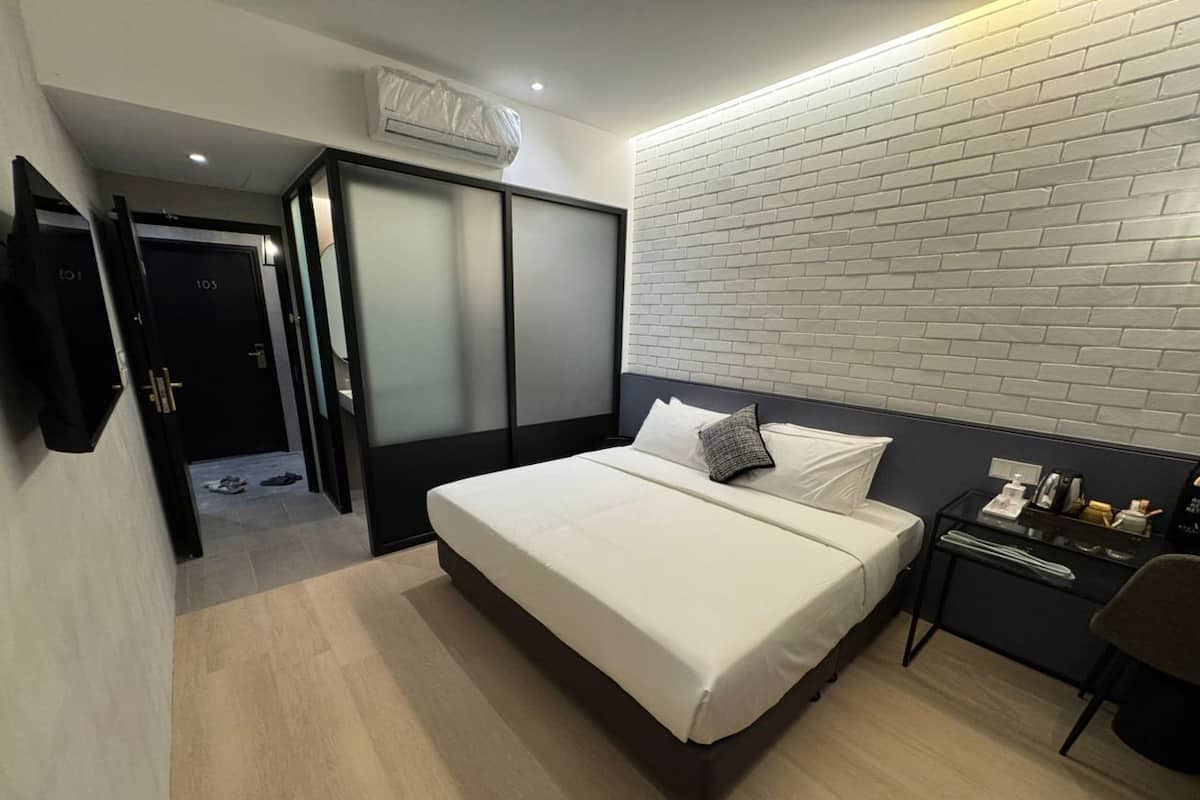 Habitación de hotel moderna con una cama, una mesita de noche, una silla y una pared con diseño de ladrillos.