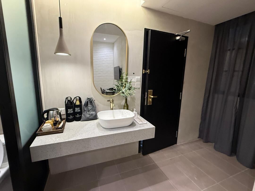 A modern bathroom with a large mirror, a white sink, and a black door.