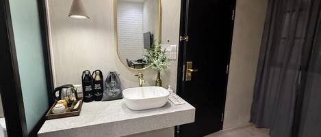 A modern bathroom with a large mirror, a white sink, and a black door.