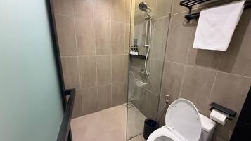 A modern bathroom with a glass-enclosed shower, a toilet, and a towel rack.