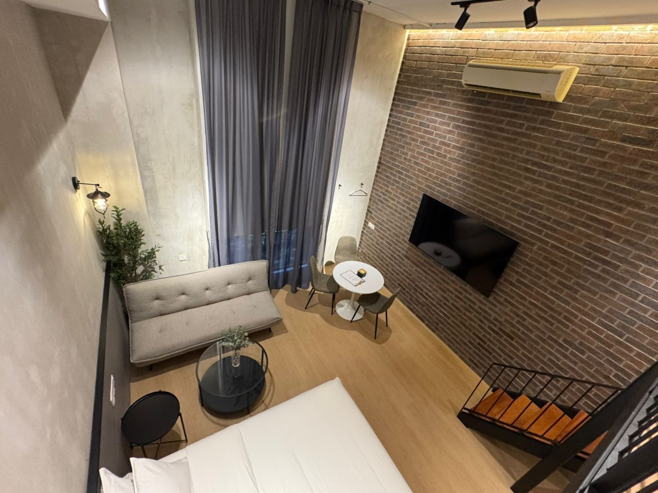 A modern interior with a sofa, round table, and a fireplace against a brick wall.