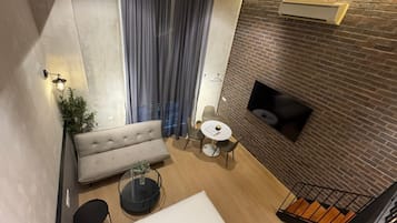 Een modern interieur met een bank, een ronde tafel en een open haard tegen een bakstenen muur.