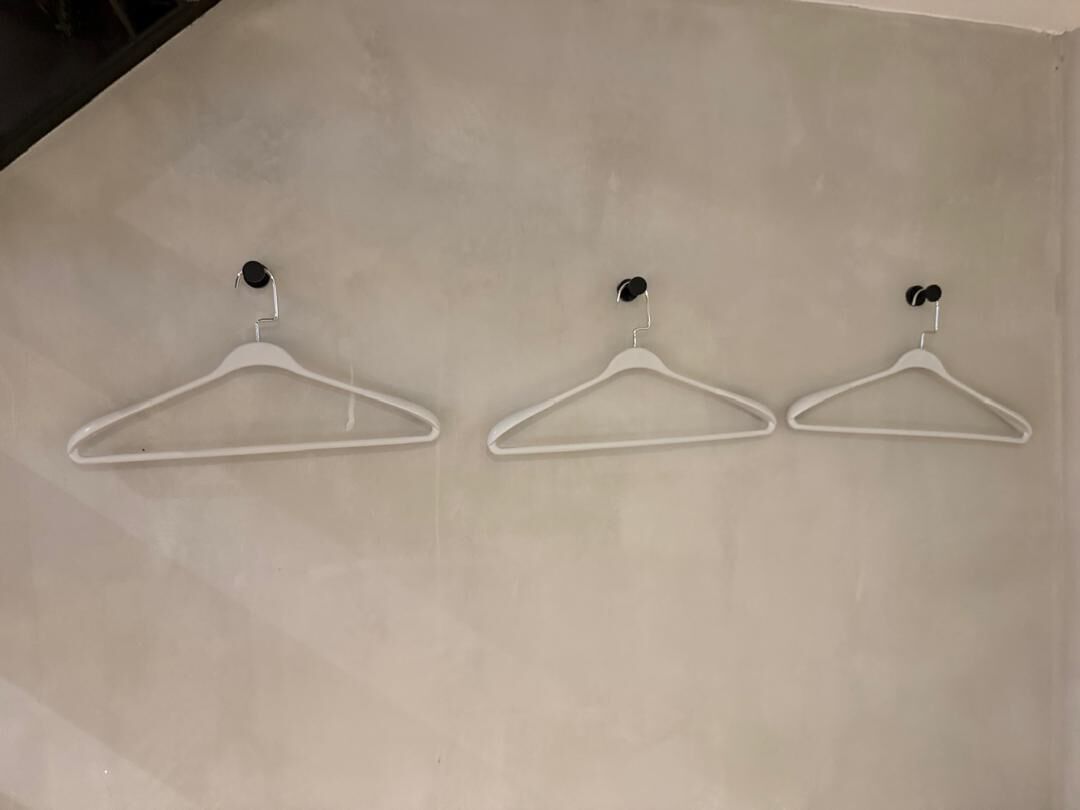 Tres perchas blancas fijadas a la pared en un espacio vacío.