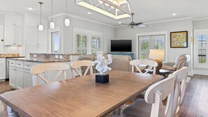 A spacious kitchen with white cabinets, a dining area with a wooden table and chairs, and a ceiling fan. - Private Pool - Gulf Views-Steps from the Beach (Cape San Blas)