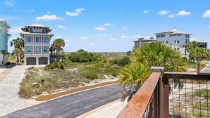 A coastal residential area with modern houses, a paved road, and palm trees. - Private Pool - Gulf Views-Steps from the Beach (Cape San Blas)