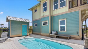 A swimming pool with a wooden deck, a small building with a blue door, and a bench. - Private Pool - Gulf Views-Steps from the Beach (Cape San Blas)