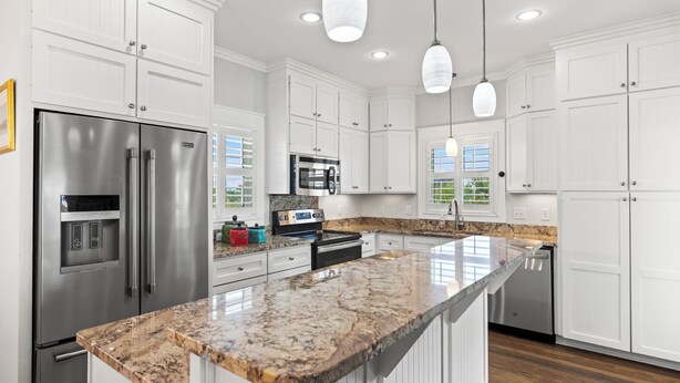 A modern kitchen with white cabinetry, stainless steel appliances, and a granite countertop. - Private Pool - Gulf Views-Steps from the Beach (Cape San Blas)
