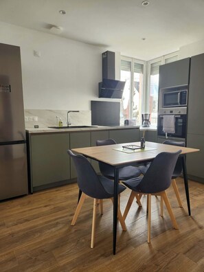 A modern kitchen with a dining table and chairs, a refrigerator, a microwave, and a window. - House by the sea (Binic-Étables-sur-Mer)