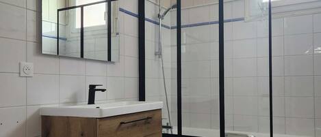 A bathroom with a wooden vanity, a mirror, a shower enclosure, and a toilet.