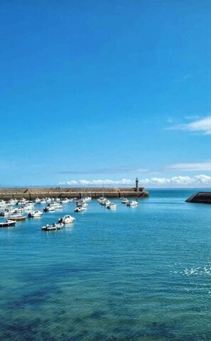 A harbor with boats docked, a lighthouse, and a clear blue sky. - House by the sea (Binic-Étables-sur-Mer)