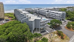 A coastal hotel with multiple balconies, a swimming pool, and a view of the ocean.