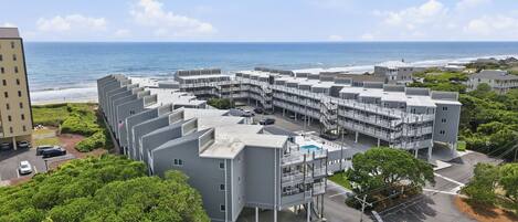 A coastal hotel with multiple balconies, a swimming pool, and a view of the ocean.