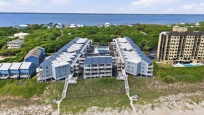 A coastal hotel with multiple buildings, a beach access area, and a view of the ocean.