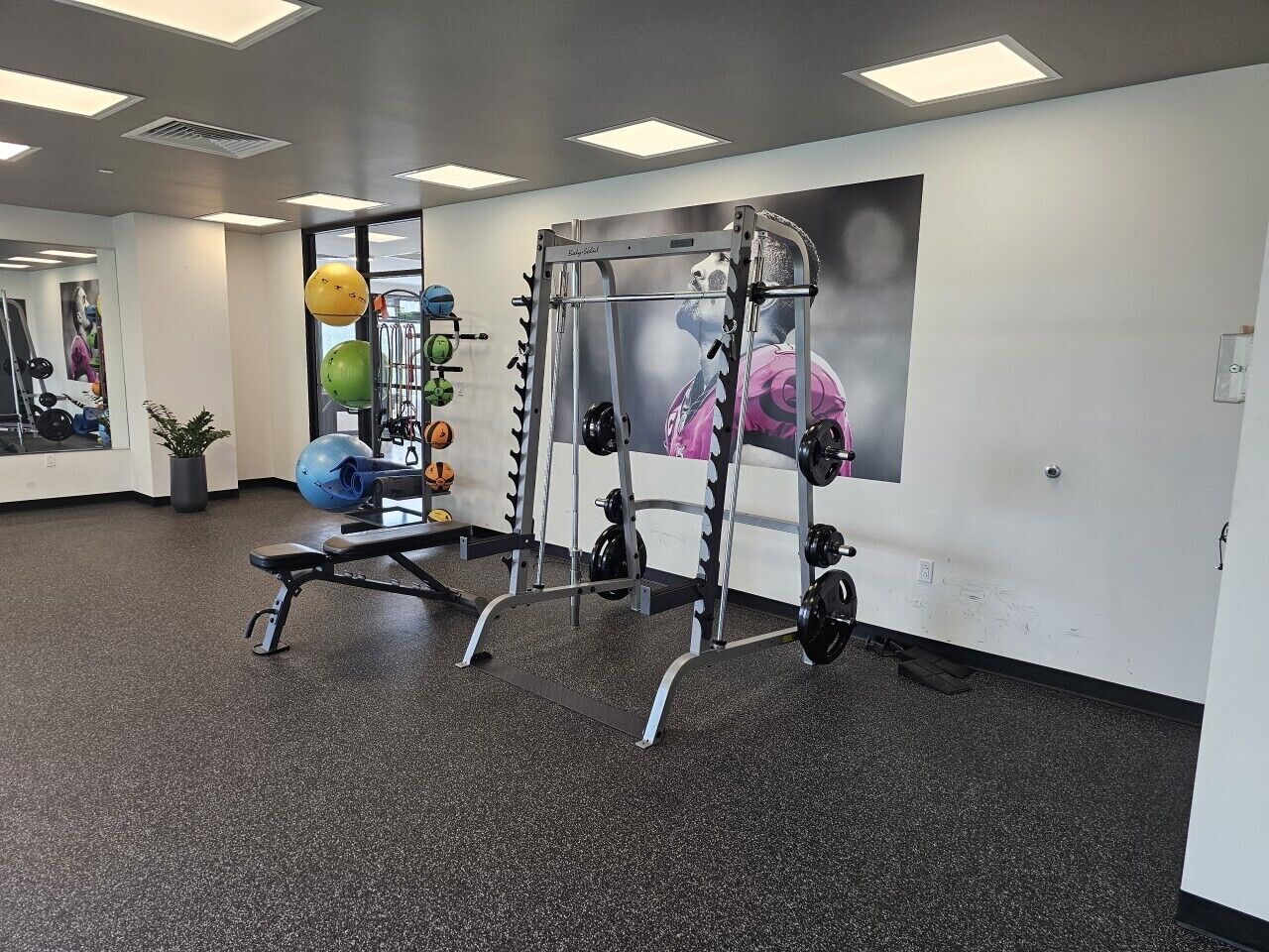 Een sportschool met trainingsapparatuur, een bank en een muur met een poster.