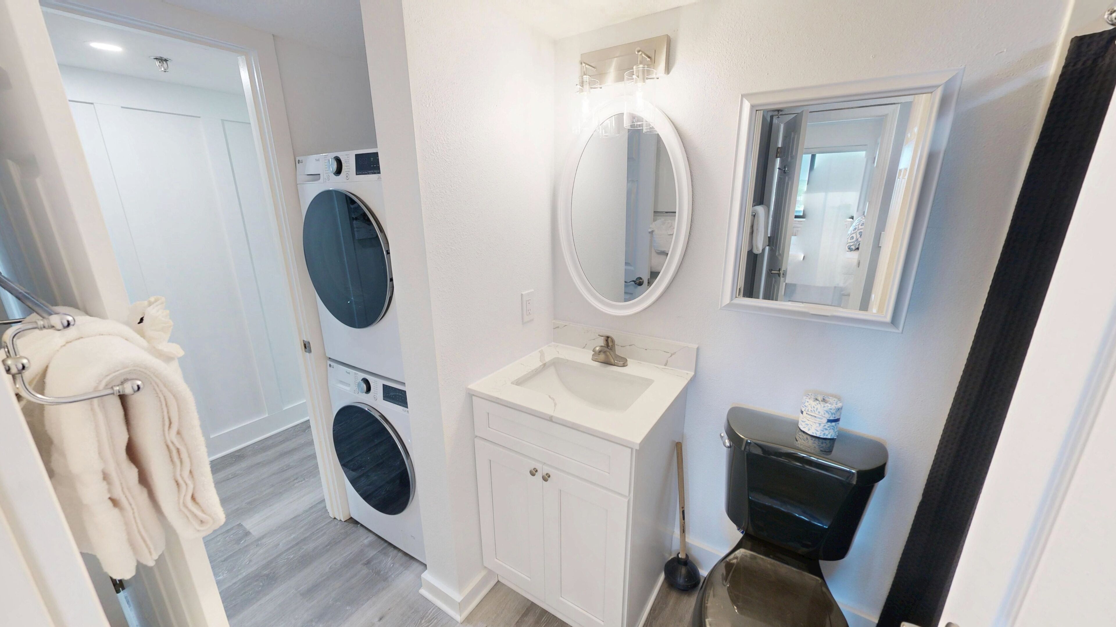 Une petite salle de bain équipée d’un lave-linge, d’un évier, de toilettes et d’un miroir.