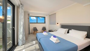 Une chambre d’hôtel avec un lit, deux chaises, un bureau et une grande fenêtre.
