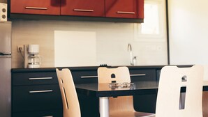 A modern kitchen with wooden cabinets, a black countertop, and a dining area with a table and chairs. - Spacious Cottage for 6 in Marminiac (Marminiac)