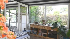 A room with a checkered sofa, a wooden desk with books, and a view of greenery outside. - SE257 - Montemarciano, one-bedroom apartment with garden and veranda (Montemarciano)