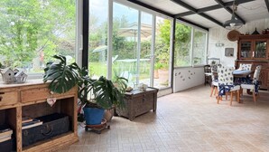 A spacious room with large windows, a wooden table, chairs, and a cabinet. - SE257 - Montemarciano, one-bedroom apartment with garden and veranda (Montemarciano)