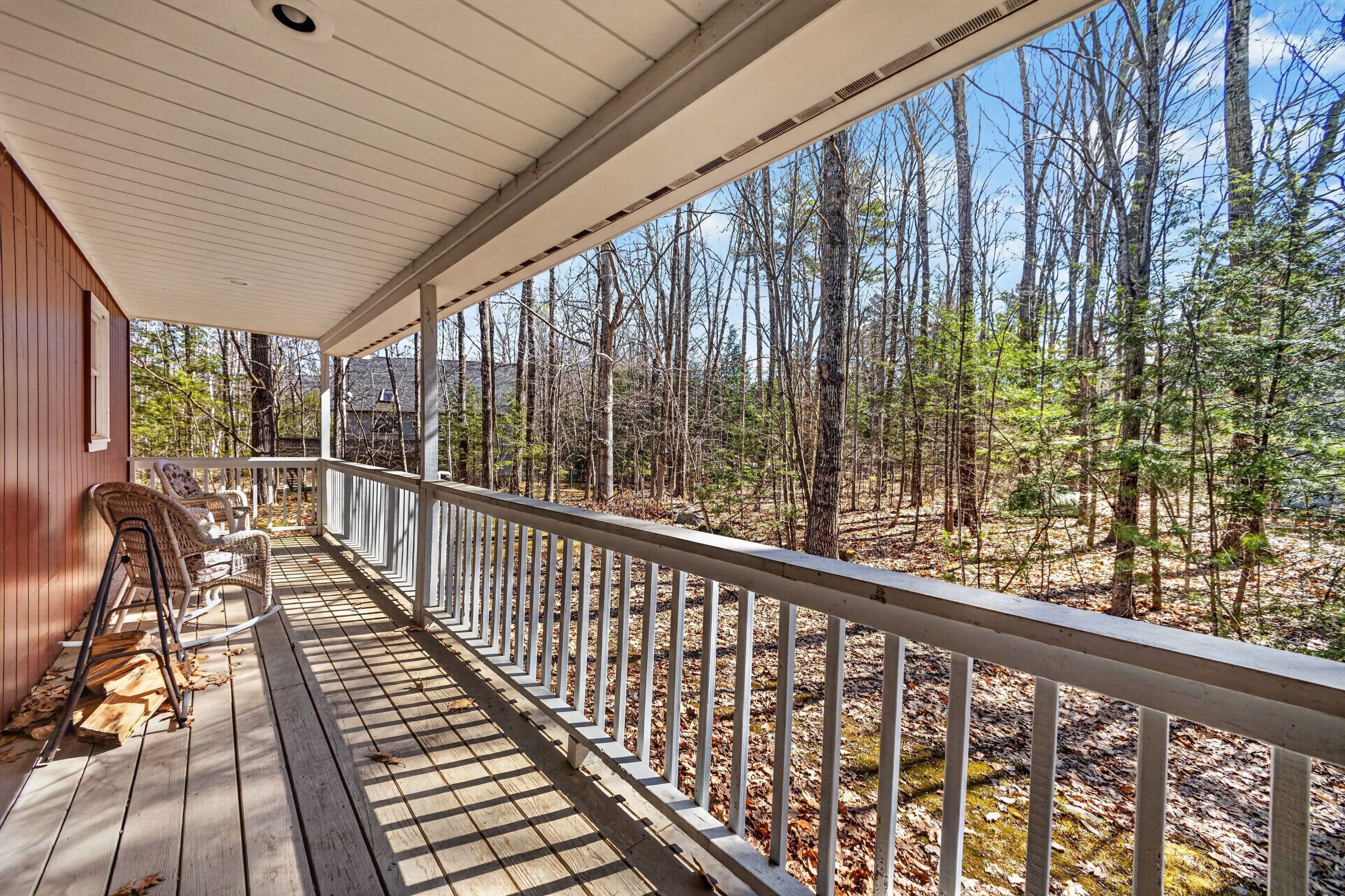 A wooden deck with a railing, overlooking a forested area.