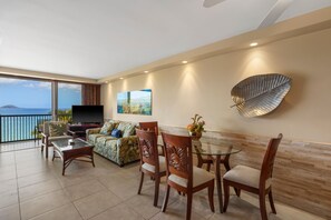 A modern living room with a balcony, a flat-screen TV, a sofa, and a dining area with chairs and a glass table. - Mana Kai Maui Resort, #804c 2 Bedroom Condo (Kihei)