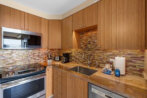 A modern kitchen with wooden cabinets, a stainless steel microwave, a toaster, and a coffee maker. - Mana Kai Maui Resort, #804c 2 Bedroom Condo (Kihei)