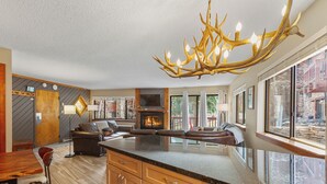 Een moderne keuken met een groot eiland, een open haard en een bijzondere lamp van gewei.
