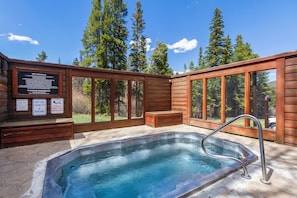 Ein Whirlpool mit Holzterrasse, ein Schild mit den Regeln für den Whirlpool und Blick auf Bäume.
