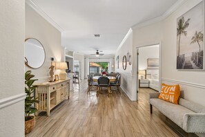 A hallway leading to a dining area with a round table, chairs, and a sofa with a cushion. - Serene Villa with Heated Pool & Arcade Near Disney (Clermont)
