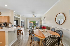 A spacious kitchen with a central island, dining area with patterned chairs, and a large mirror on the wall. - Serene Villa with Heated Pool & Arcade Near Disney (Clermont)