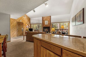 Ein modernes Interieur mit Holzbalkendecke, Kamin, Essbereich und großen Fenstern.