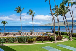 A resort with a pool area, palm trees, and a view of the ocean.