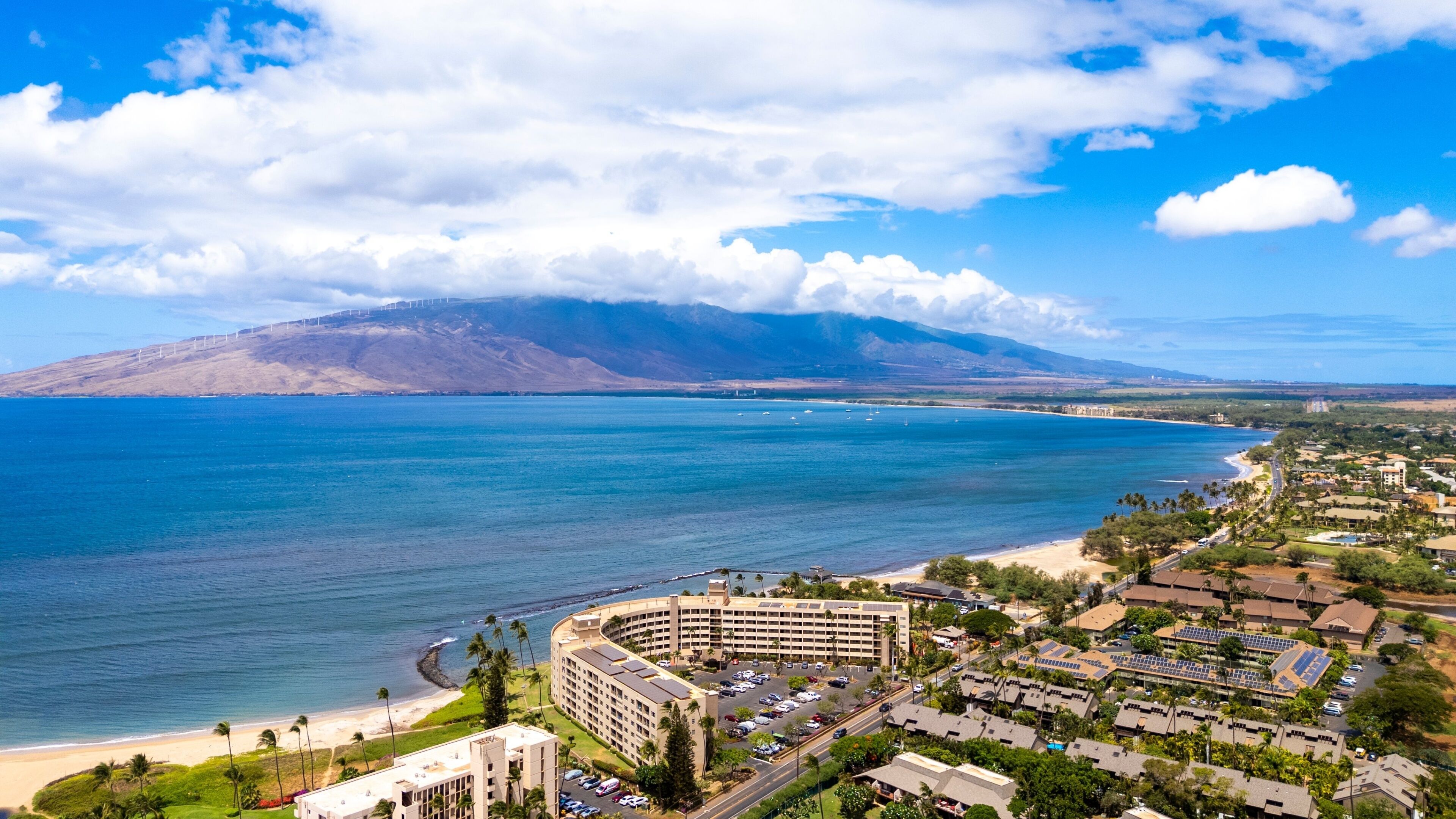 A coastal resort with a large hotel, beachfront, and a mountain in the background.