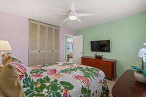 A bedroom with a bed, a dresser, a television, and a ceiling fan. - Menehune Shores, #206 2 Bedroom Condo (Kihei)