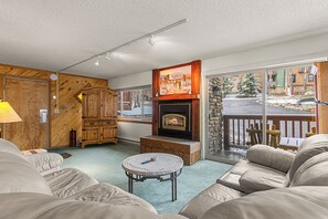 Ein gemütliches Wohnzimmer mit Kamin, Holzmöbeln und Blick ins Freie.