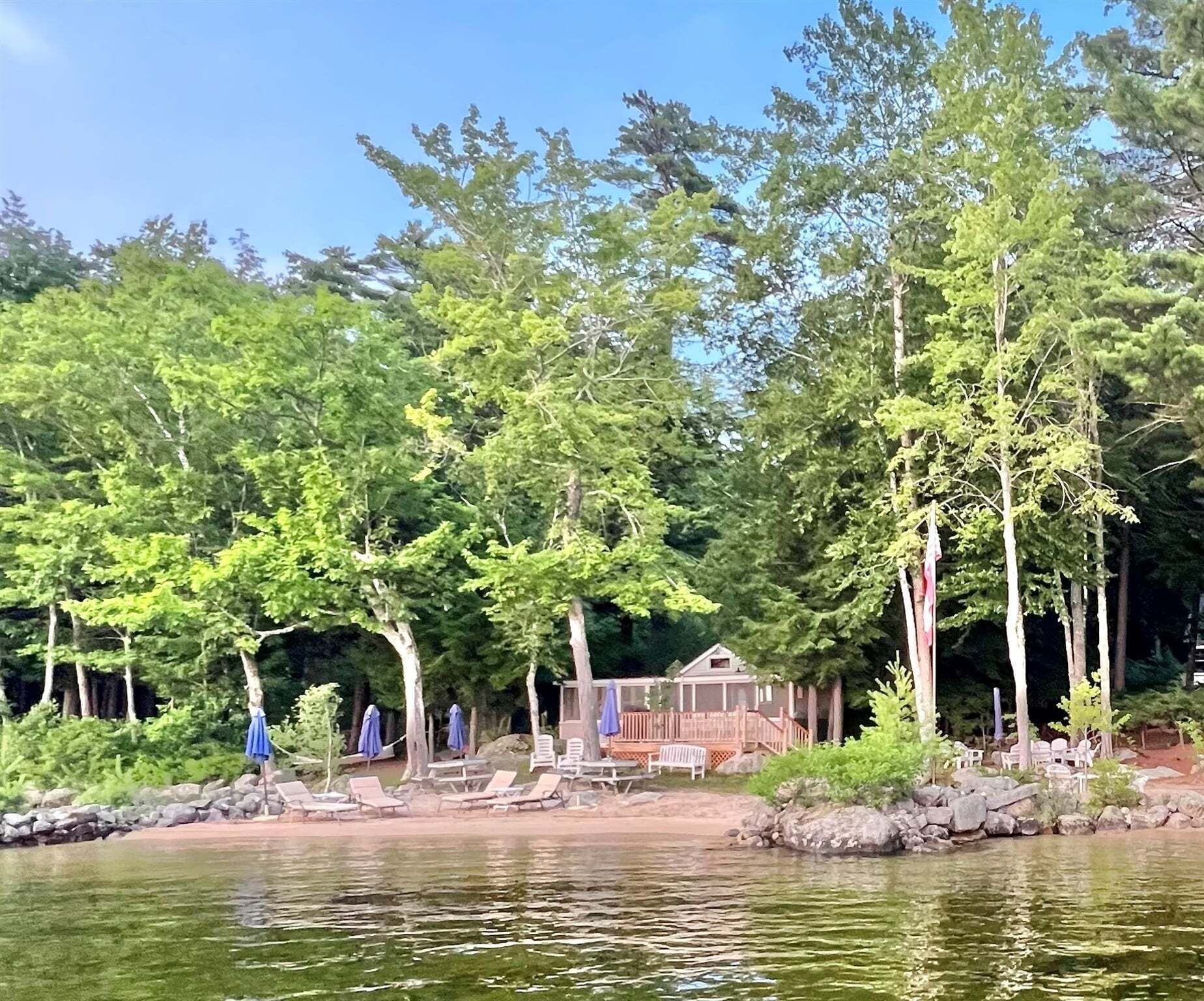 A lakeside cabin with outdoor seating and a dock.